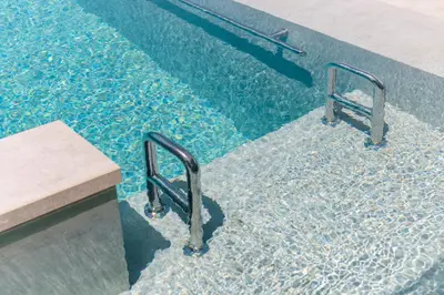 a swimming pool with two metal rails in the water at Grand Blue Villas Lachania in Lachania