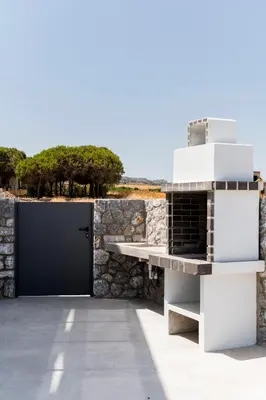a pizza oven on a patio with a stone wall at Grand Blue Villas Lachania in Lachania