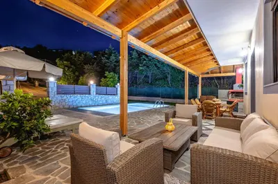 an outdoor patio with a table and chairs and a pool at Villa Rafaella2 in Koskinou