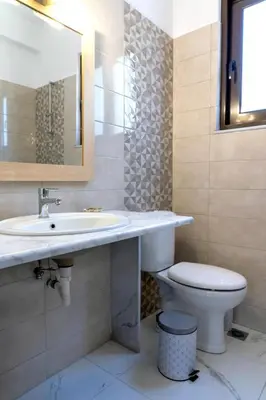 a bathroom with a sink and a toilet and a mirror at Villa Rafaella2 in Koskinou