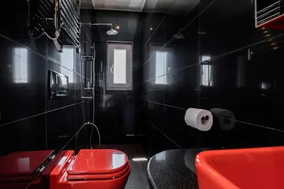 a black bathroom with a red toilet and a roll of toilet paper at Diamond Villa in Gennadi
