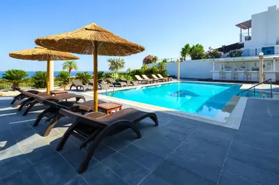 a pool with chairs and umbrellas next to a building at Diamond Villa in Gennadi