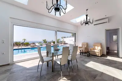 a dining room with a table and a view of the ocean at Diamond Villa in Gennadi