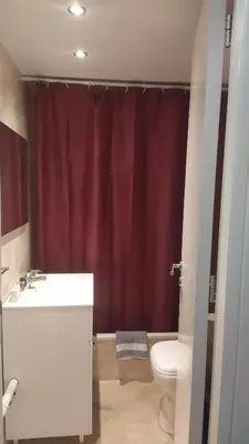 a bathroom with a toilet and a red shower curtain at Danai House in Rhodes Town
