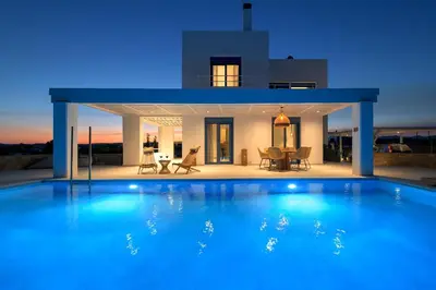 a large blue swimming pool in front of a house at Astrea Villas in Lachania