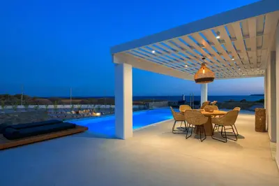 a patio with a table and chairs under a pergola at Astrea Villas in Lachania