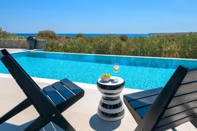 a pair of chairs sitting next to a swimming pool at Astrea Villas in Lachania