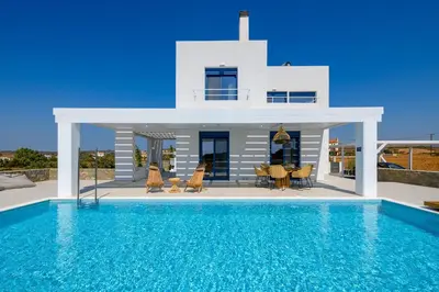 a villa with a swimming pool in front of a house at Astrea Villas in Lachania
