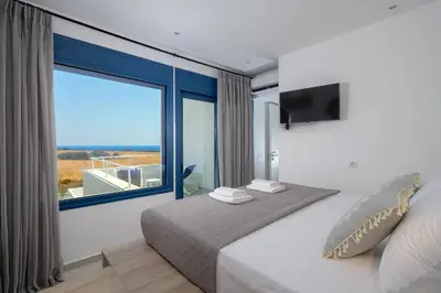 a bedroom with a bed with a large window at Astrea Villas in Lachania