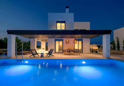 a villa with a swimming pool at night at Astrea Villas in Lachania