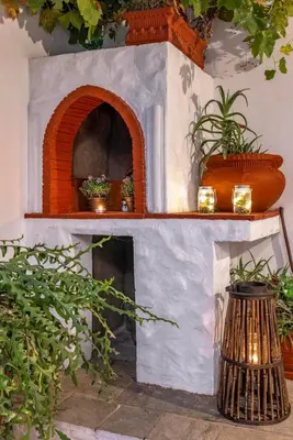 a brick fireplace with two shelves and some plants at Beautiful historic house in Koskinou