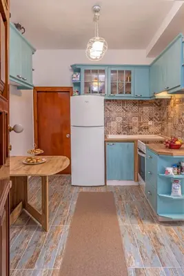a kitchen with blue cabinets and a white refrigerator at Beautiful historic house in Koskinou