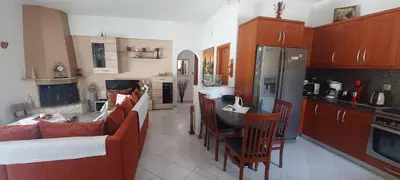 a kitchen with couches and a table and a refrigerator at Nila's Villa in Koskinou