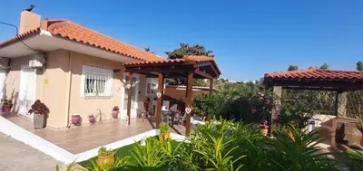 a house with a patio with two wooden pergolas at Nila's Villa in Koskinou