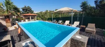 a swimming pool with chairs and an umbrella at Nila's Villa in Koskinou