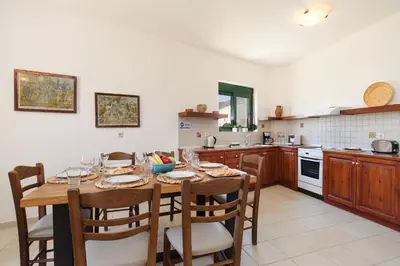a kitchen with a wooden table with chairs and a tableablish at Villa Meitani in Kattavía