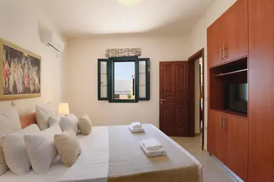 a bedroom with a bed with white pillows and a television at Villa Meitani in Kattavía