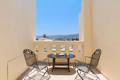 a balcony with a table and chairs and a window at Villa Meitani in Kattavía