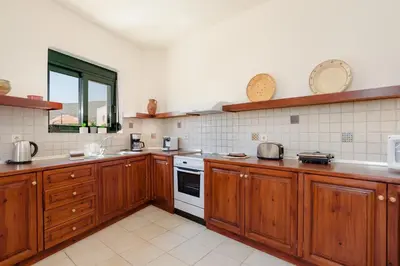 a large kitchen with wooden cabinets and white appliances at Villa Meitani in Kattavía