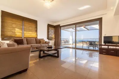 a living room with a couch and a tv and a table at Villa Cleopatra Private Heated Pool, Tennis & Football in Koskinou