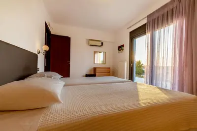 a bedroom with two beds and a large window at Villa Cleopatra Private Heated Pool, Tennis & Football in Koskinou