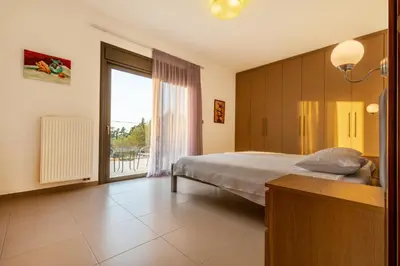 a bedroom with a bed and a large window at Villa Cleopatra Private Heated Pool, Tennis & Football in Koskinou