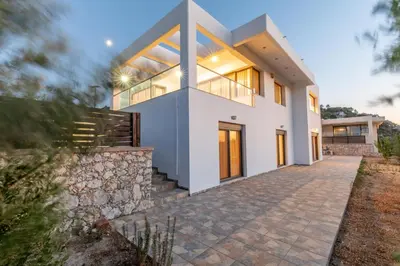 a large white house with a stone wall at Villa Cleopatra Private Heated Pool, Tennis & Football in Koskinou