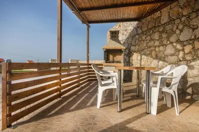 a table and chairs on a patio with a stone wall at Villa Cleopatra Private Heated Pool, Tennis & Football in Koskinou