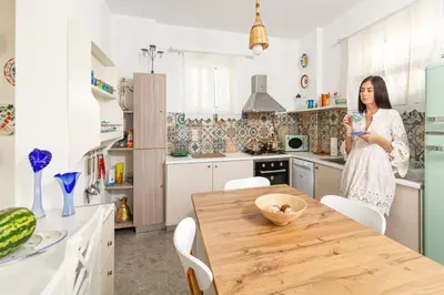 a woman standing in a kitchen with a wooden table at CHRYSANTHI'S STONE HOUSE in Afantou