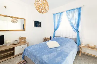 a bedroom with a blue bed and a television at CHRYSANTHI'S STONE HOUSE in Afantou