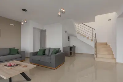 a living room with a couch and a table and stairs at Mika Villa in Afantou