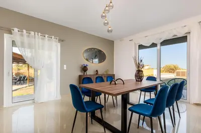 a dining room with a wooden table and blue chairs at Mika Villa in Afantou