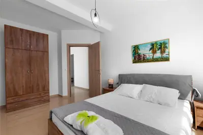 a bedroom with a white bed with a wooden cabinet at Mika Villa in Afantou
