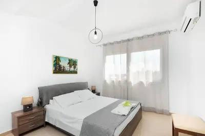 a white bedroom with a bed and a window at Mika Villa in Afantou