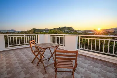 a table and two chairs on a balcony with the sunset at Mika Villa in Afantou