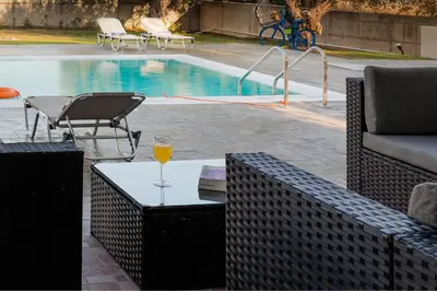a glass of wine sitting on a table next to a pool at Mika Villa in Afantou