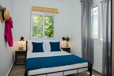 a bedroom with a bed with blue pillows and a window at Potnia House in the center of Rhodes in Rhodes Town