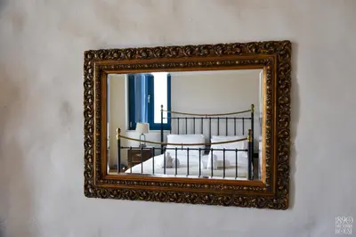 a mirror on a wall with a bed in it at 1890 Fanourakis House in Halki