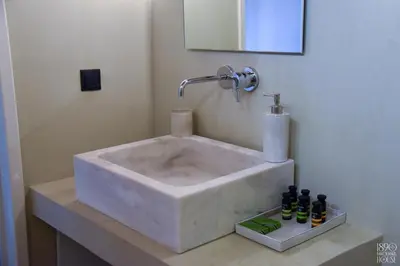 a white sink in a bathroom with bottles on a counter at 1890 Fanourakis House in Halki