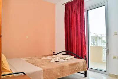 a bedroom with a bed with a red curtain at ANTONIOS apartments in Archangelos