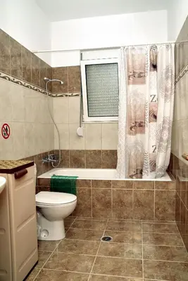 a bathroom with a toilet and a tub and a window at ANTONIOS apartments in Archangelos