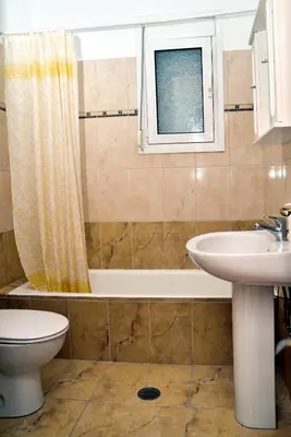 a bathroom with a sink and a tub and a toilet at ANTONIOS apartments in Archangelos