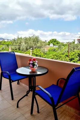 a balcony with two chairs and a table and flowers at ANTONIOS apartments in Archangelos