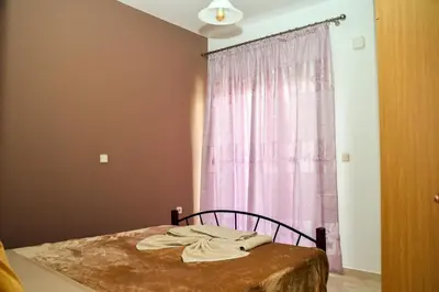 a room with a bed with a pink curtain at ANTONIOS apartments in Archangelos