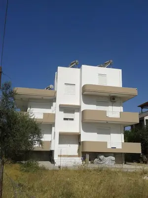 a white apartment building in front of a field at ANTONIOS apartments in Archangelos