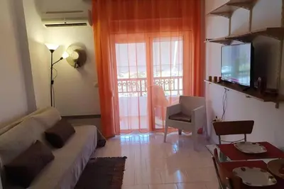 a living room with a couch and a television at Amarantou Apartment - Rhodes City Center in Rhodes Town