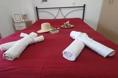 a red bed with two towels and a hat on it at Amarantou Apartment - Rhodes City Center in Rhodes Town