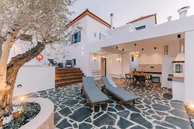 a patio with a tree and a table and chairs at Kalathos Square luxury suites in Kalathos