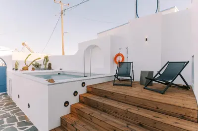 two chairs on a wooden deck with a swimming pool at Kalathos Square luxury suites in Kalathos