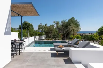 a patio with a table and chairs next to a swimming pool at Kalathos Square luxury suites in Kalathos